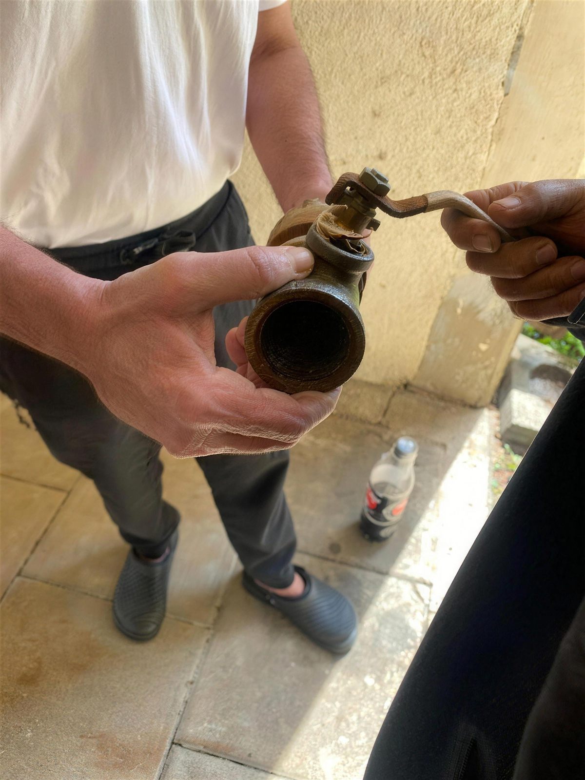 הידיים של עמנואל מחזיקות שסתום חלוד שפורק מהקיר